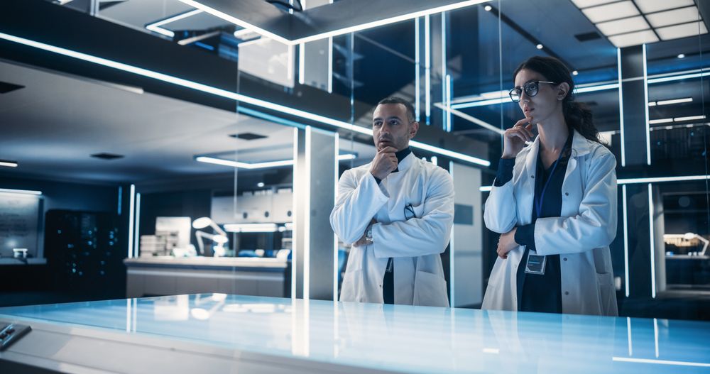 Multiethnic Male And Female Scientists Standing In the High-Tech Laboratory Next to The Table.