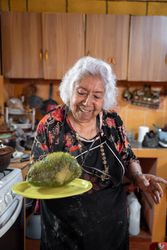 Portrait of older woman smiling showing a fresh cooked chayote