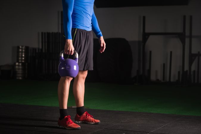 Man holding kettlebell on floor in gym