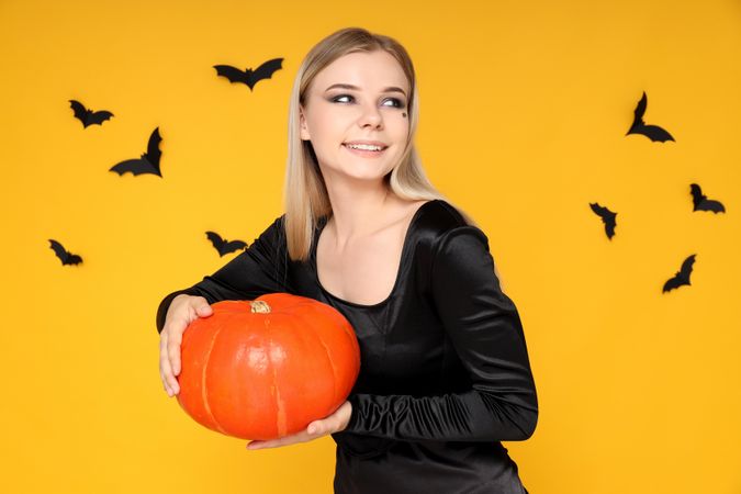 Concept of Halloween, young woman on yellow background