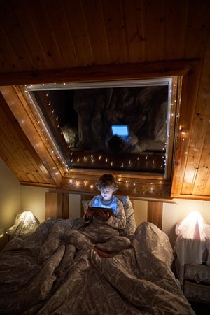 Boy browsing tablet in dark bedroom