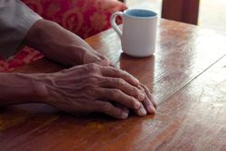 Hands of person resting on table with coffee cup
