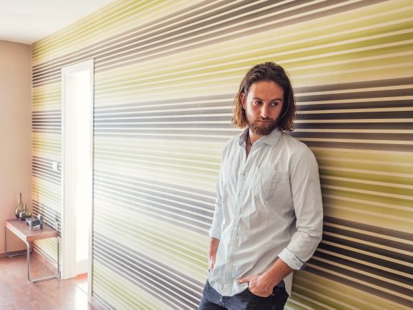 Handsome male standing with hand in pockets in modern room