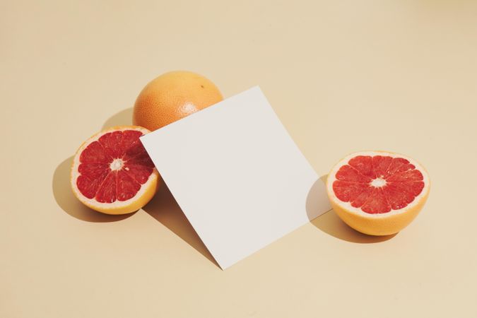 Grapefruit halved with paper card on beige background