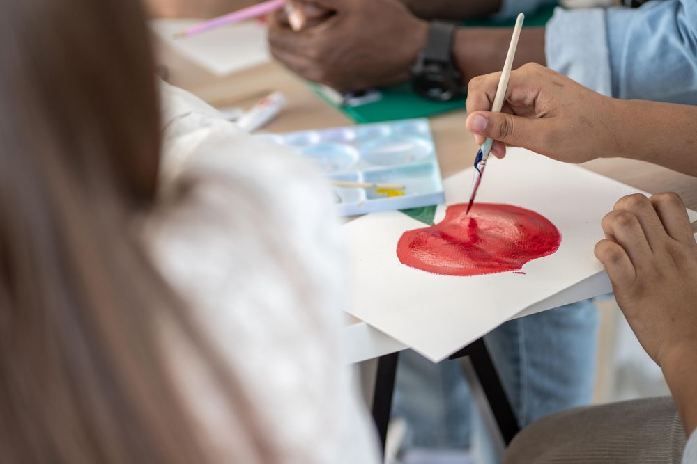 Close up of classroom table with students sitting painting