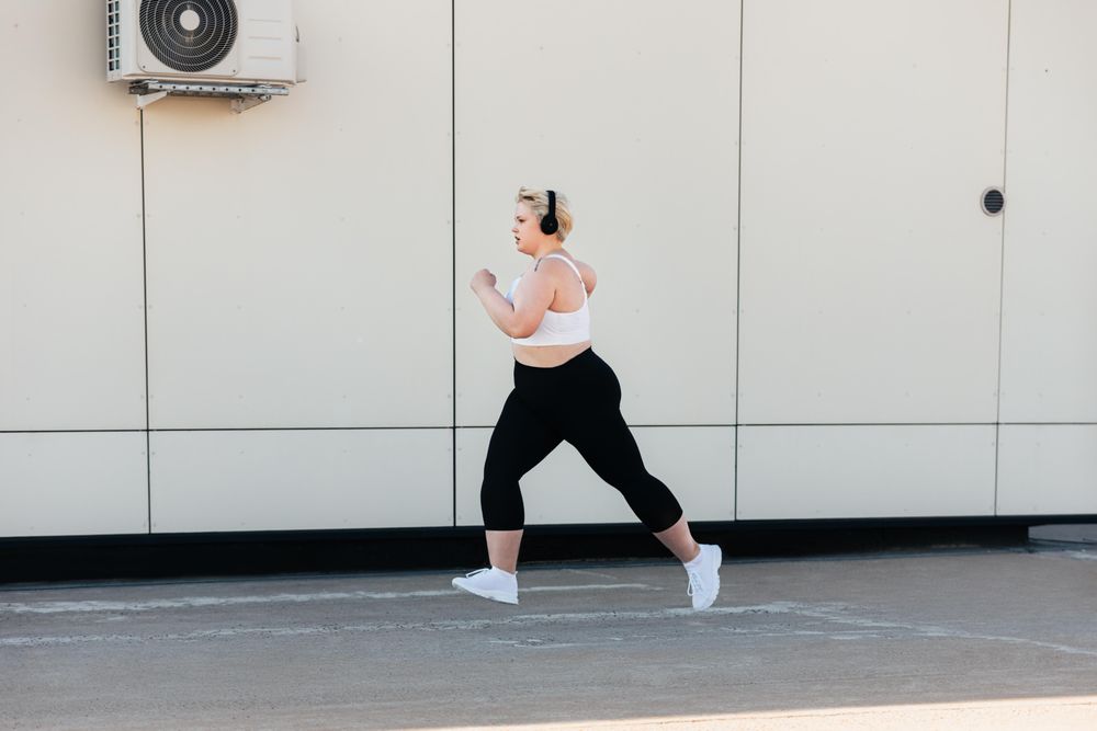 Curvy female in sports clothes jogging outdoors