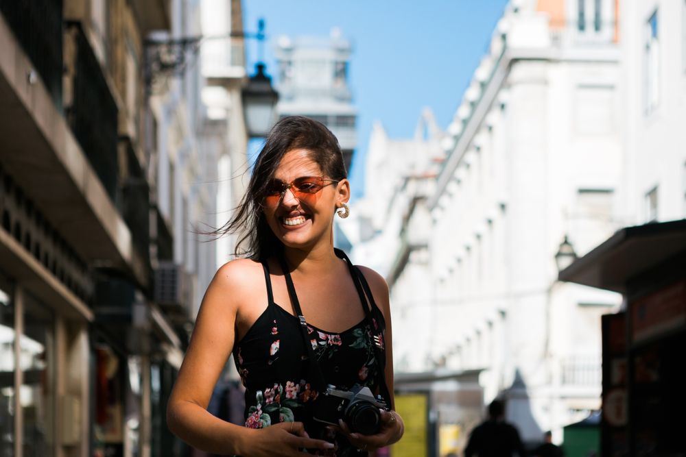 Carefree woman holding a camera on the street