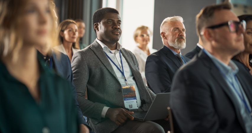 Black Man Sitting in a Crowded Audience at a Business Conference.