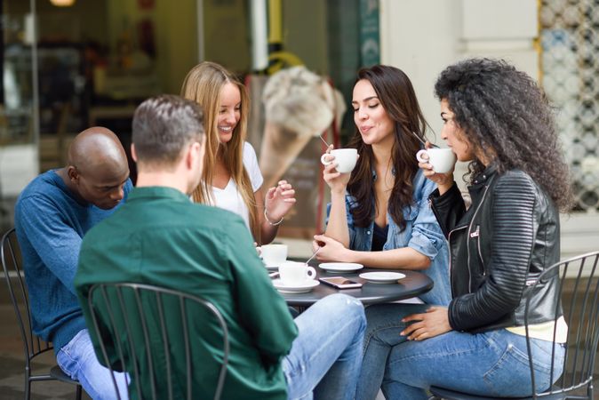 Multi-ethnic group of male and female friends socializing over coffee