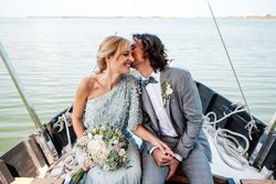 Content newlyweds smiling and holding hands while sitting on boat