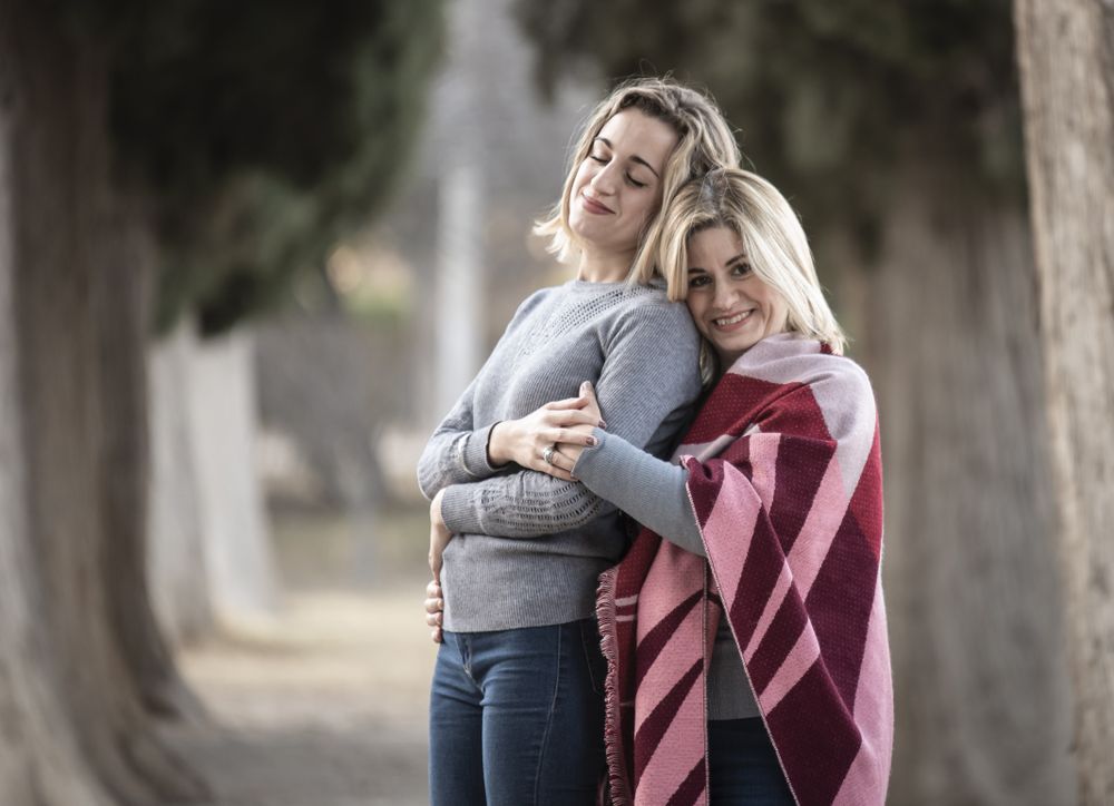 Mother and daughter hugging near trees