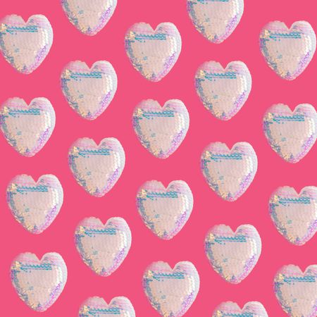 Iridescent sequins heart pattern on bright pink background