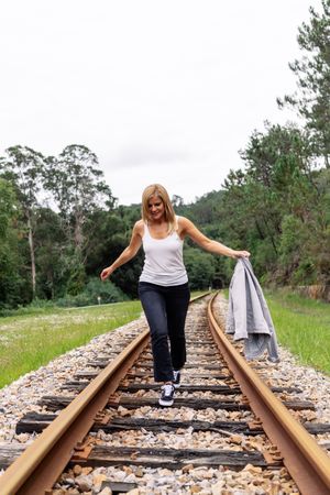 Woman walking along railway though greenery part of road
