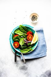 Top view of delicious spinach salad with lemon slice