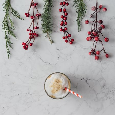 Christmas branches and berries on marble table with coffee