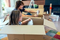Father and son playing car racing with cardboard boxes
