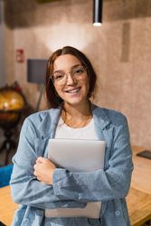 Happy female manager with laptop in workplace