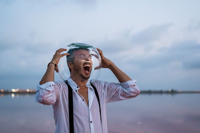 Distressed man with fish tank on head screaming