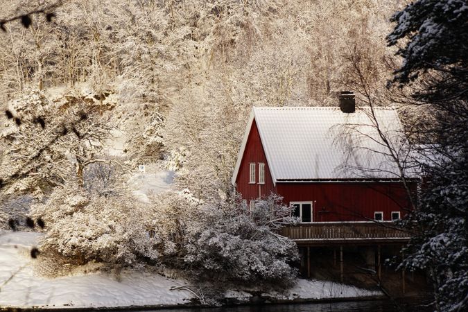 Lonely house in snowy forest on riverside