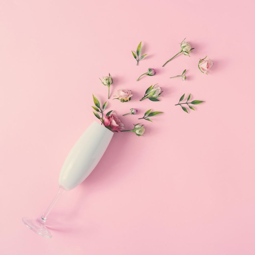 Champagne glass with spring flowers against pink background