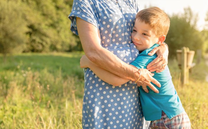 Happy grandson hugging to woman outdoors