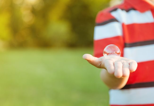 Cute boy showing soap bubble in his open hand