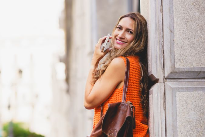Latin woman leaning on an urban facade in the city