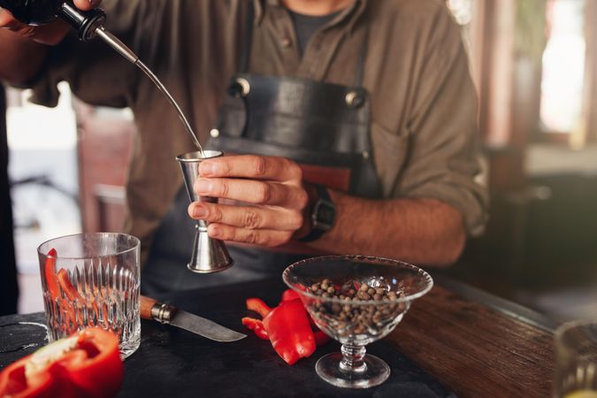 Closeup of bartender hands pouring alcoholic drink into a jigger
