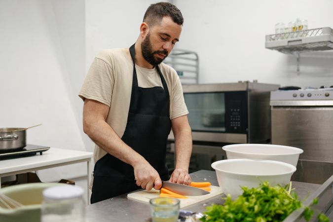Young chef cutting carrots