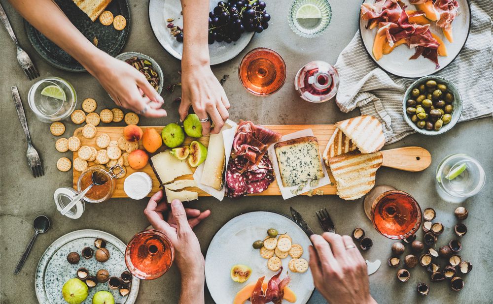 Charcuterie board with hands reaching for cheese and fig