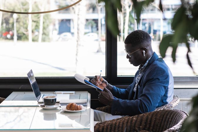 Focused Black male entrepreneur taking notes during work in cafe
