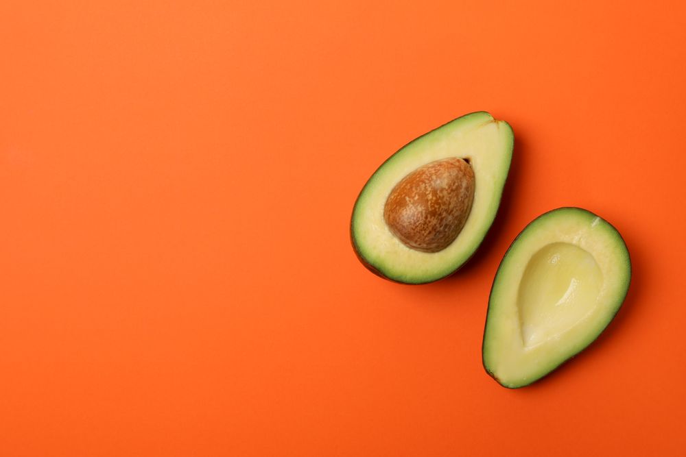 Ripe fresh avocado on orange background, top view