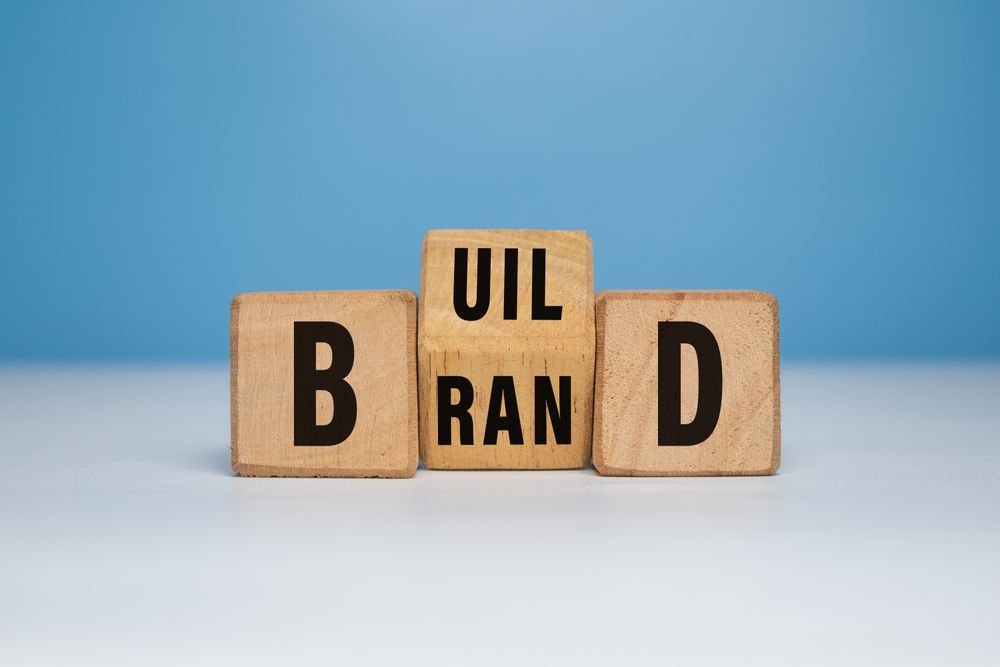 Build brand words symbol with turned wooden block. build your brand concept. isolated on blue background