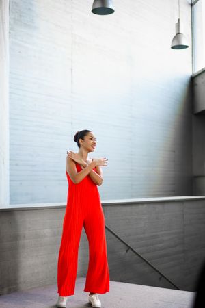 A confident young woman poses in a vibrant red outfit, showcasing her strength and beauty