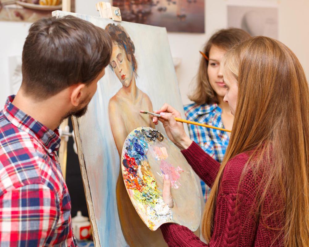 Male and female colleagues observes a woman painting a nude