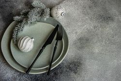 Top view of Christmas table setting with pine branch and snowy baubles and copy space