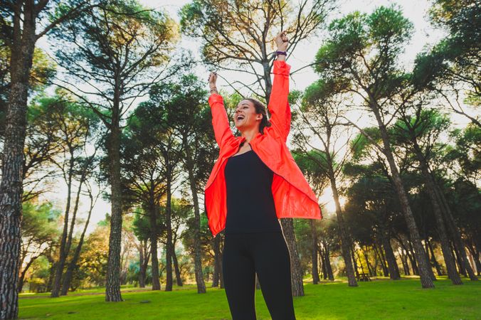 Excited sportswoman with arms raised in park