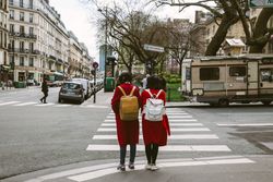 Back view of two girls in red coats and backpacks on pedestrian lane 5RwnR4
