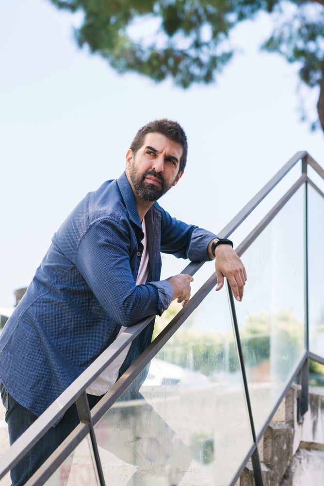 Serious man in denim leaning on outdoor stairs rail