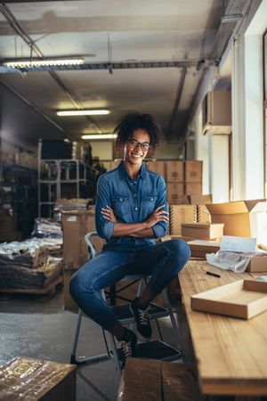 Smiling woman sitting at the desk with parcel boxes around