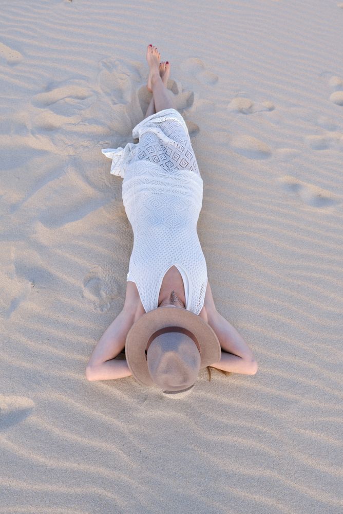 Woman in white dress relaxing on sand