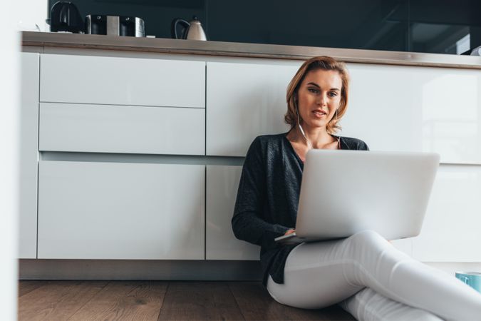Woman sitting on floor in home with laptop