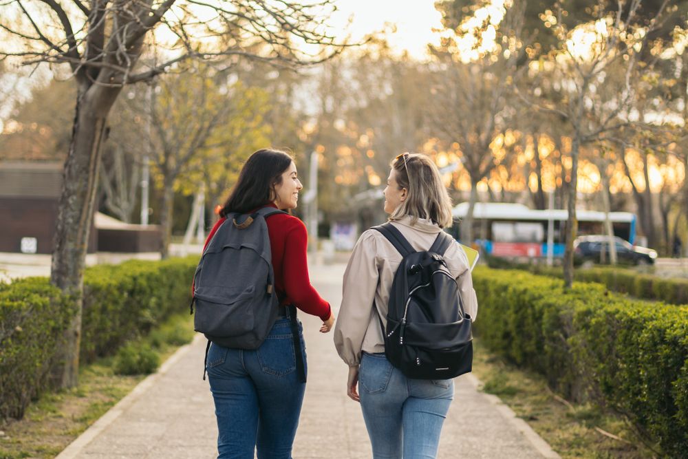 Back view of two students walking and talking in campus