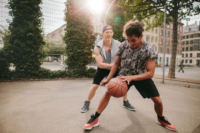 Friends playing basketball on court and having fun