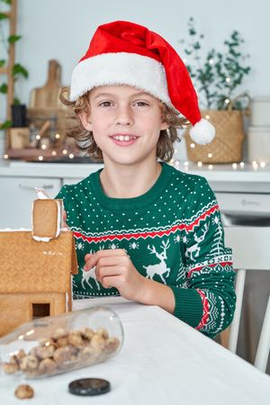 Boy making gingerbread house in kitchen