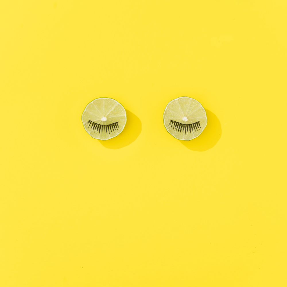 Lime fruit with eyelashes on bright yellow background