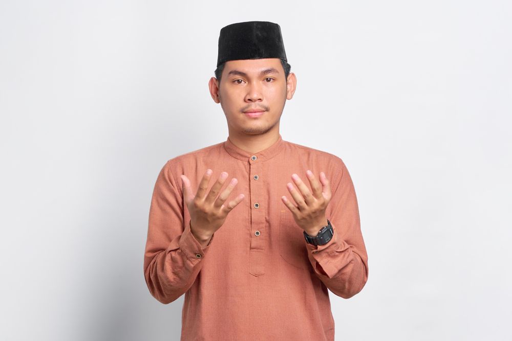 Solemn Muslim man praying in kufi head wear