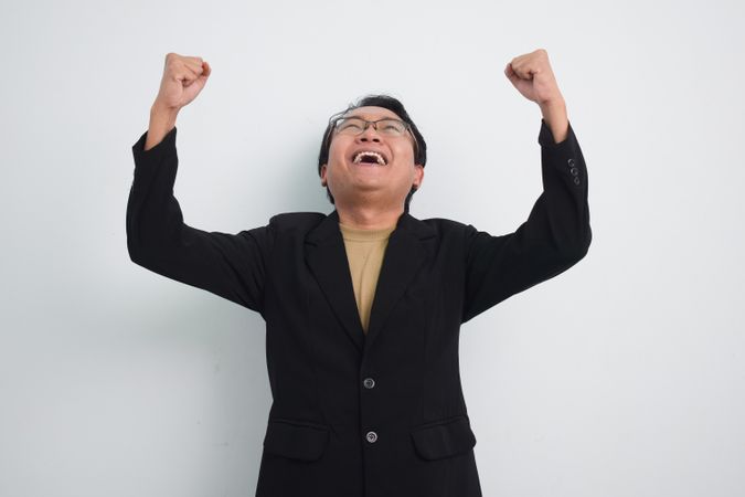 Happy Asian businessman looking up after a win