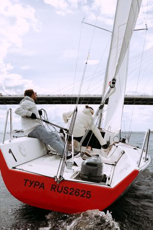 Two people on light and red sail boat