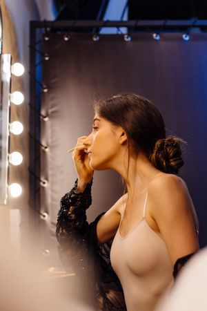 female in peignoir applying makeup